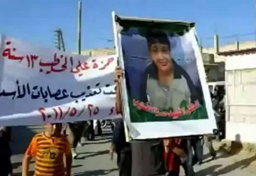 מפגינים נושאים את דיוקנו של חמזה אל-חטיב, מתוך סרטון שהועלה לרשת