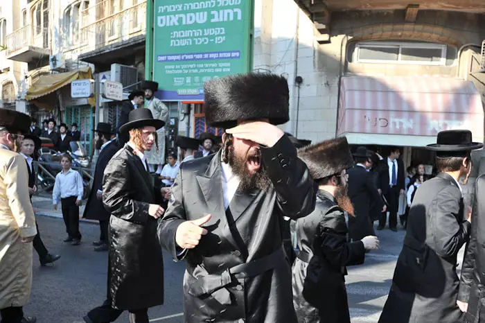 השוטרים הודפים את החרדים שחסמו את הכביש חזרה אל השכונה