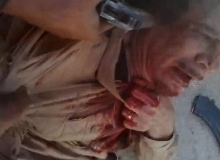 אקדח מוצמד לראשו של קדאפי החי לאחר לכידתו, מתוך אחד הסרטונים שפורסמו