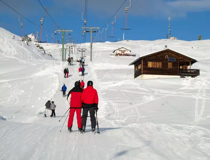 שני גולשים לובשים בגדי סקי אדומים ועומדים ליד רכבל שלג