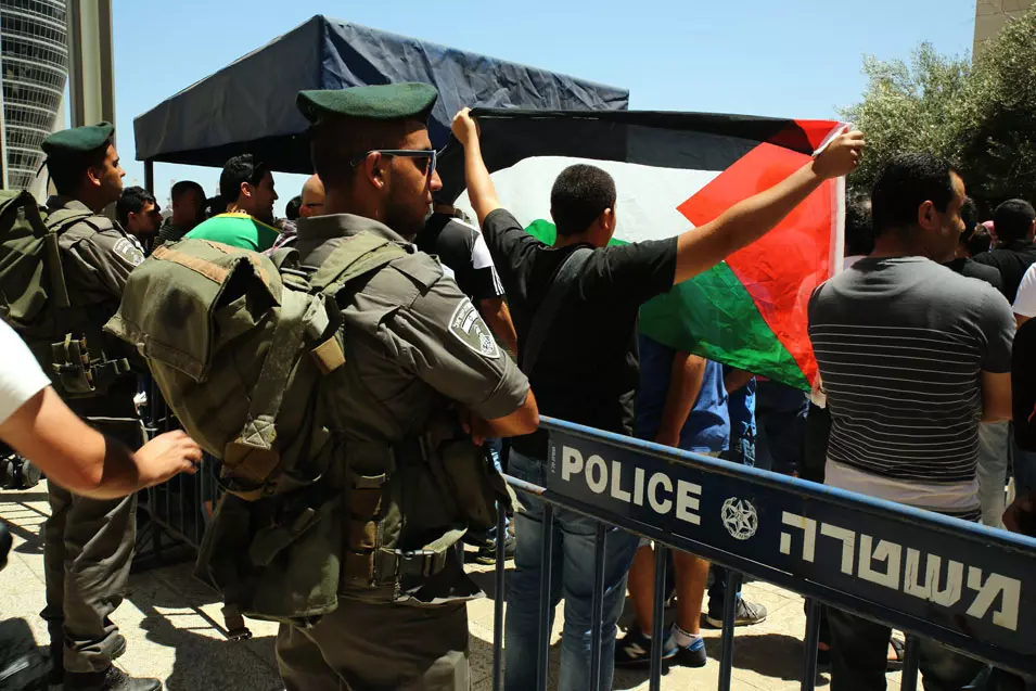 המפגינים מניפים דגלי פלסטין וקוראים "צדק לנאשמים"