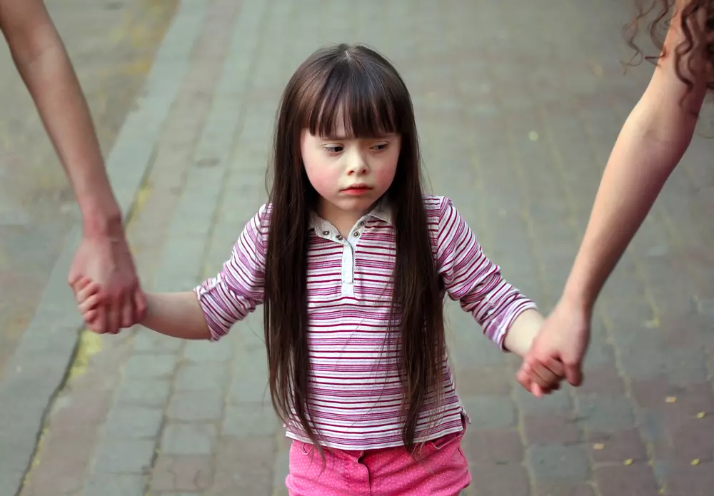 ילדה עצובה מחזיקה בידיים של אחיותיה