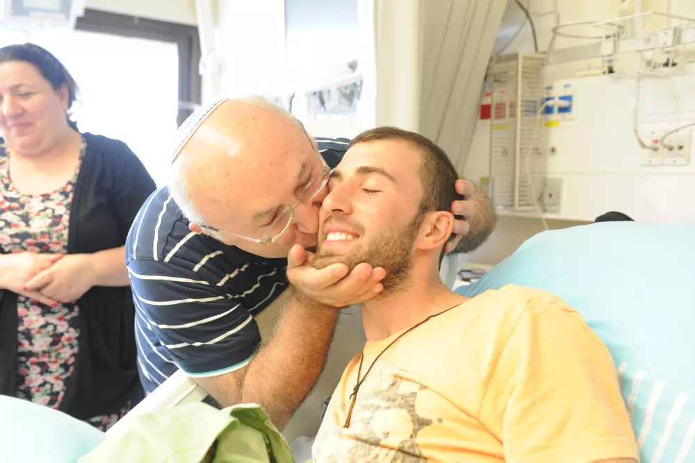 אחד הפצועים שנחתו בישראל מקבל נשיקה מאביו בבית החולים שיבא
