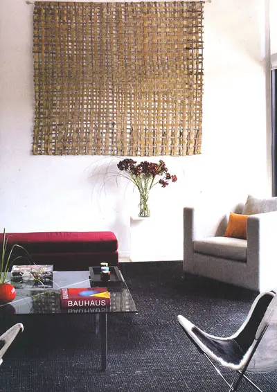 בסלון שטיח שחור עם מסגרת קנבס ואריג טבעי על הקיר