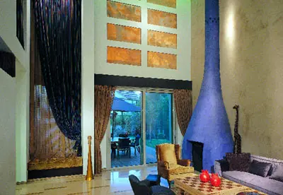 קירות הסלון מטויחים בטיוח גס והקמין בנוי מבטון ומצופה בטיח אקרילי בצבע כחול
