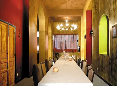 במרכז חלל האירוח שולחן ארוך. מימין קיר המטבח עם נישות צבועות בירוק. משמאל קיר צבוע בלכות מגוונות. הצבעים והלכות של טמבור