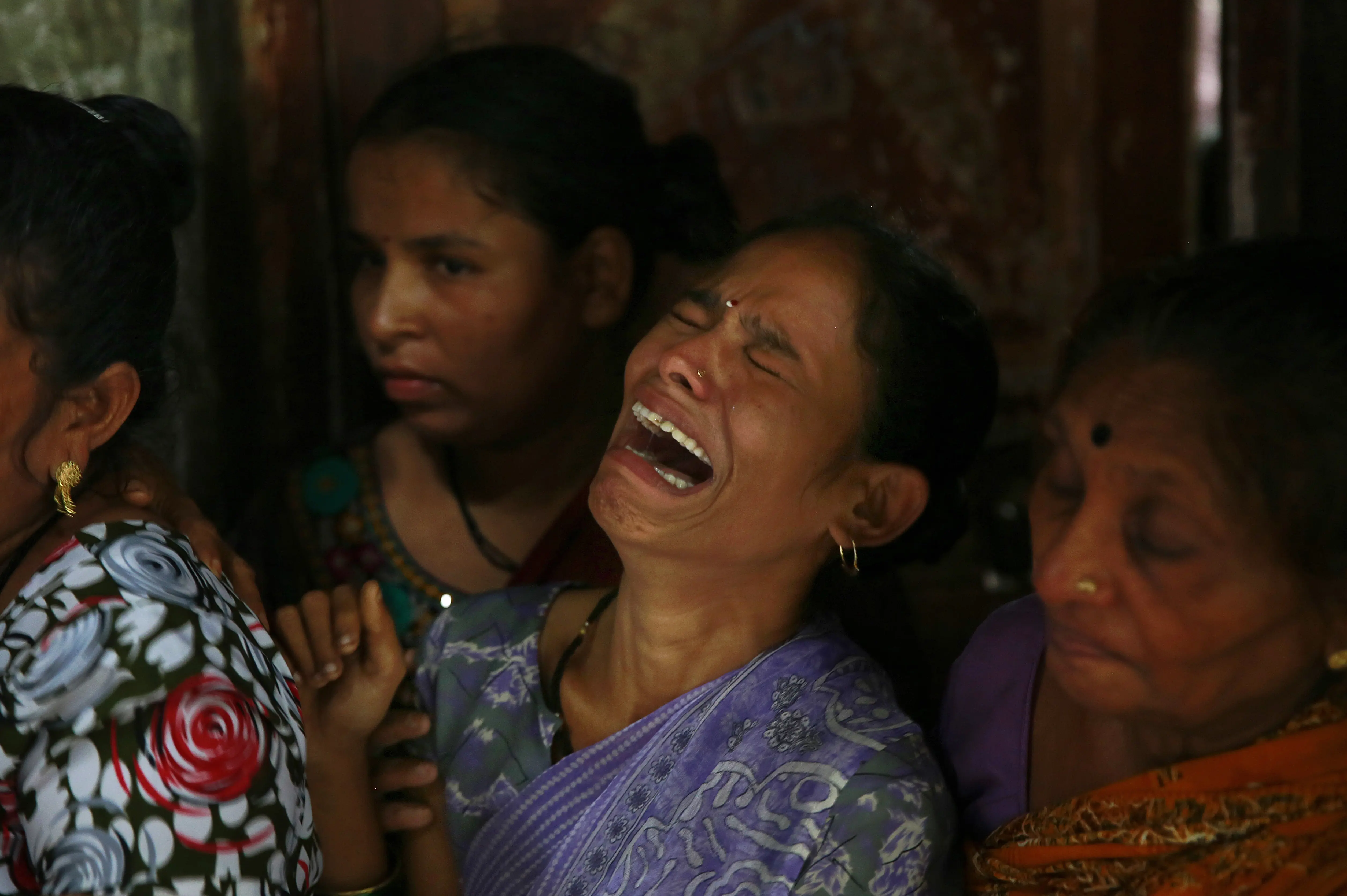 נשים בוכות בהלווית אחד מעשרות הרוגים מהרעלת אלכוהול מזויף במומבאי שבהודו ב-2015