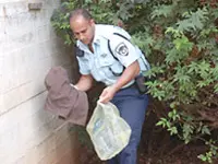 שוטר מכניס את מכנסי האסיר של סלע לשק, לאחר מציאתם. לא עדכנת את המטה?