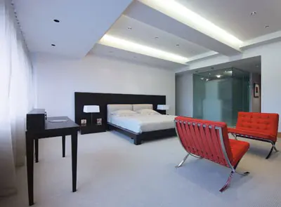 חדר השינה הוא אי של שינה ורוגע, הכורסאות האדומות על השטיח הלבן יוצרות אמירה חד משמעית