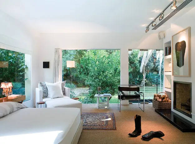 בחדר השינה המרכזי רהיטי מעצבים ועתיקות. מול המיטה ניצב אח לבנים