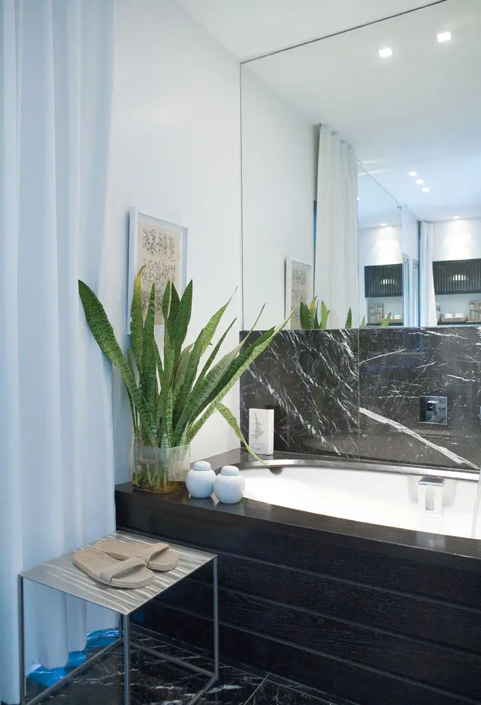 כל חדרי האמבטיות בבית מעוצבים בשיש שחור, קירות לבנים ועץ אלון מושחר