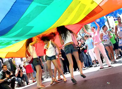 נערות רוקדות מתחת לדגל הגאווה במצעד, היום