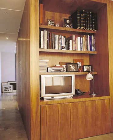 בחדר העבודה קיר עץ משמש מצד אחד כספריית מדפים לטלוויזיה ולספרים  ומצד שני הוא חלק מקובייה שבתוכה שירותים ומקלחת
