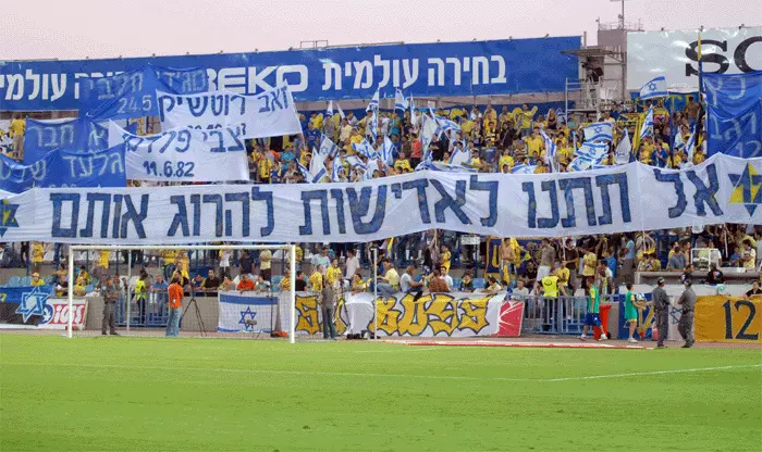אוהדי מכבי תל אביב מניפים שלטים בעד החזרת החטופים