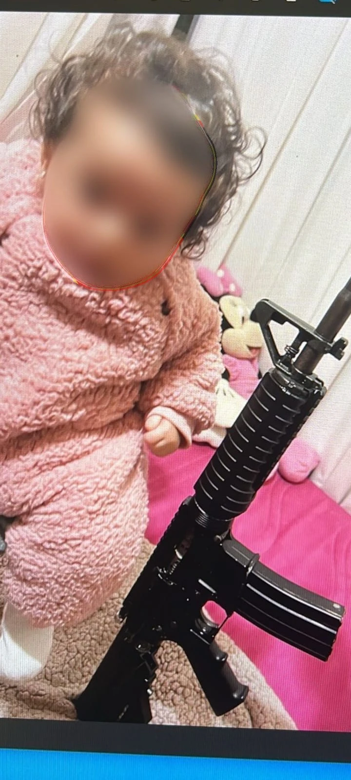 ילדה שצולמה ליד נשק, ככל הנראה M16