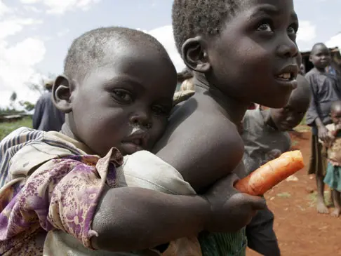 ילד מקניה נושא על גבו את אחותו הקטנה, המשפחה גורשה מהכבר עקב ריב בין שבטים