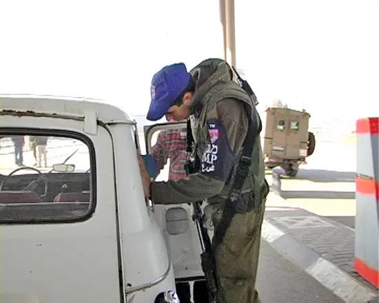 חייל צה"ל בודק רכב פלסטיני במחסום