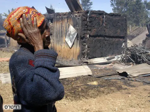 אישה קניתית עומדת מחוץ לכניסה שבה נשרפו למוות 30 אנשים במהלך המהומות לאחר הבחירות בקניה