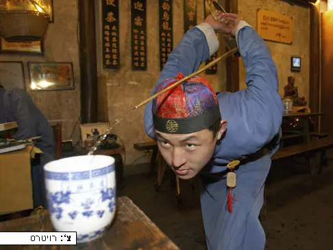 מלצר לבוש בתלבושת מסורתית של שולשלת צ'ינג מוזג תה, סין