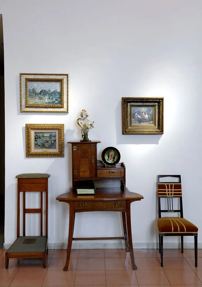 על הקיר בכניסה למסדרון, ריהוט עץ של המעצב Serrurier Bovy, שולחן כתיבה ומצדו השמאלי כיסא תפילה