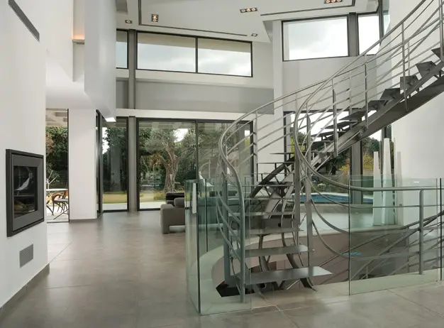 מבט מהכניסה לכיוון הסלון מבליט את המרכיבים המיוחדים, גרם מדרגות ברזל, ניתוקים בתקרה ובקירות וקיר מרחף היורד מהקומה העליונה