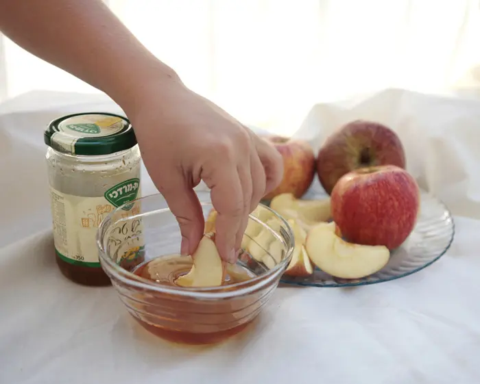 ידו של עורך מותש טובלת תפוח בדבש