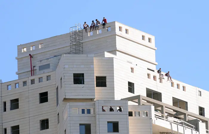 פועלים צופים במשחק מגג במגרש בפתח תקוה