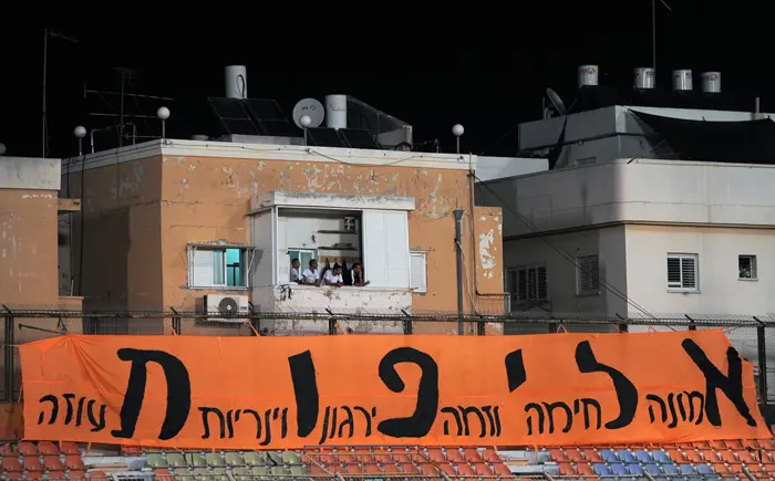 אוהדים משקיפים מהמרפסת בשכונת התקוה לפני משחק של בני יהודה תל אביב