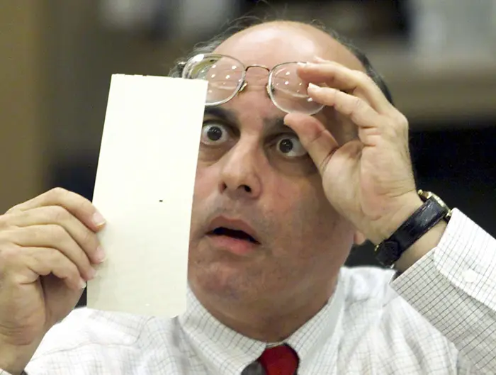חבר בוועידת הבחירות בפלורידה בודק פתק הצבעה לנשיאות ארצות הברית במהלך הספירה החוזרת, 23 בנובמבר 2000
