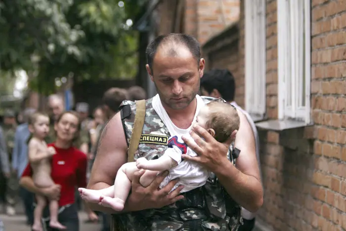 שוטר רוסי נושא תינוק שחולץ מבית ספר בבסלן עליו השתלטו מורדים צ'צנים, 2 בספטמבר 2004