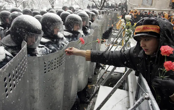 אזרחית אוקראינה מציעה פרחי ציפורן לחיילים השומרים על משרדי הנשיא בקייב בזמן המהפכה הכתומה, 24 בנובמבר 2004