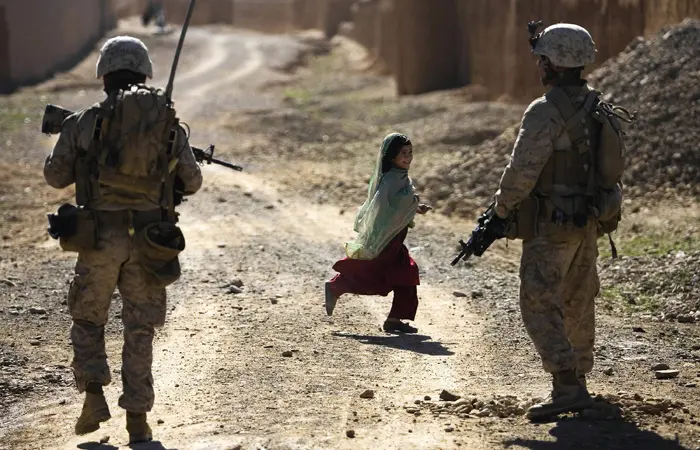 ילדה אפגנית רצה ליד חיילים אמריקאים באפגניסטן