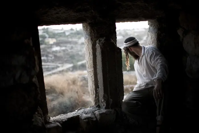 שי יושב על עדן החלון במבנה נטוש ליד בת עין שבגוש עציון