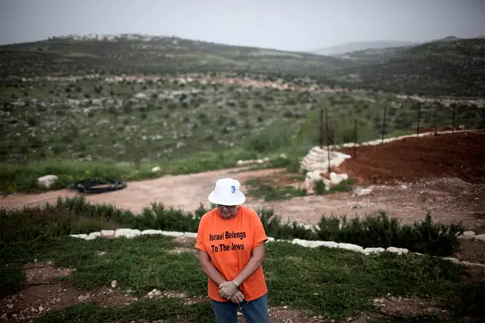 אישה עומדת על גבול הישוב קדומים שבשומרון, על חולצתה כיתוב "ישראל שיכת ליהודים"