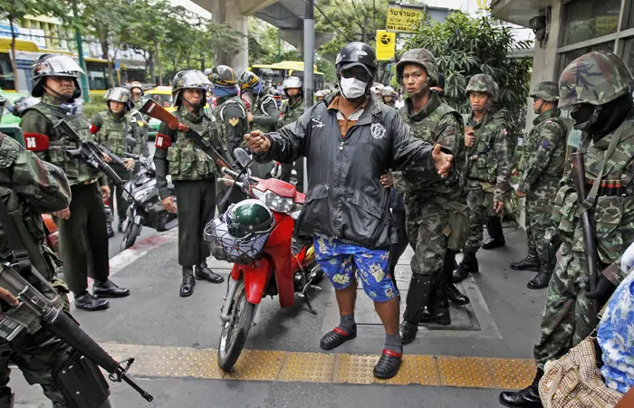 אנשי החולצות האדומות התקהלו ליד ביתו של ראש הממשלה בבנגקוק. חייל עורך בדיקה גופנית של חשוד