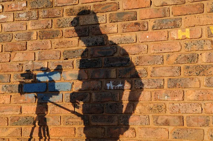 דמותו של צלם משתקפת מקיר בדרום אפריקה
