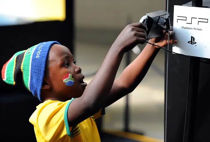ילד דרום אפריקאי לובש חולצה של נבחרת דרום אפריקה ומשחק בפלייסטיישן