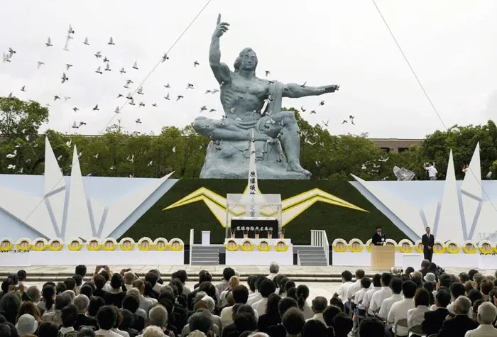 יונים עפות על רקע פסל השלום בפארק השלום בנגסאקי יפן, בטקס לציון יום השנה להטלת הפצצה על העיר