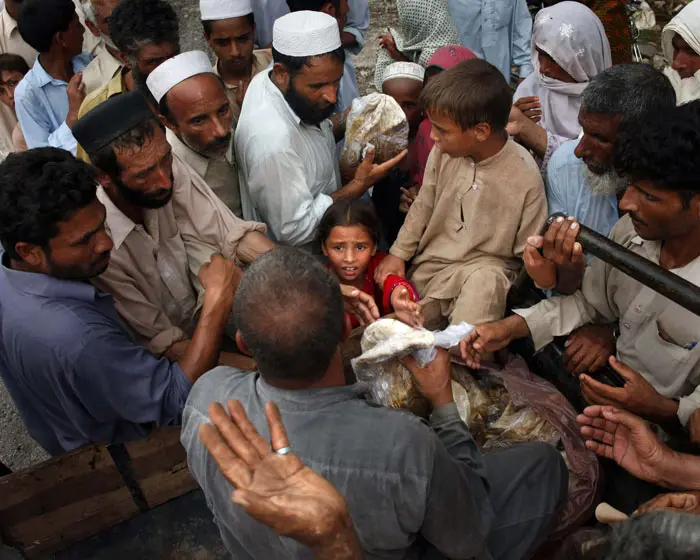 קורבנות השיטפונות בפקיסטן בעמדת חלוקת סיוע
