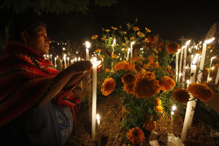 אישה מדליקה נרות ליד קבר ב"יום המתים"