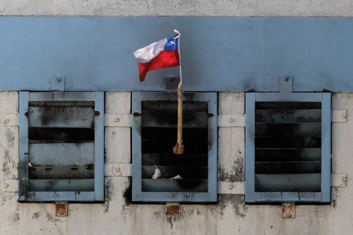 אסיר מנופף בדגל צ'ילה מחלון כלא סן מיגל בסנטיאגו, לאחר השריפה בכלא שבה נהרגו 83