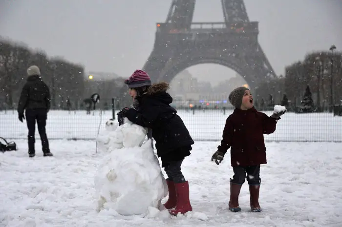 ילדים משחקים בשלג מול מגדל אייפל בפריז