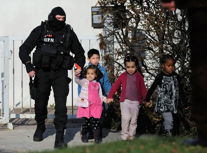 שוטר מלווה את אחרוני הילדים ששוחררו מהגן