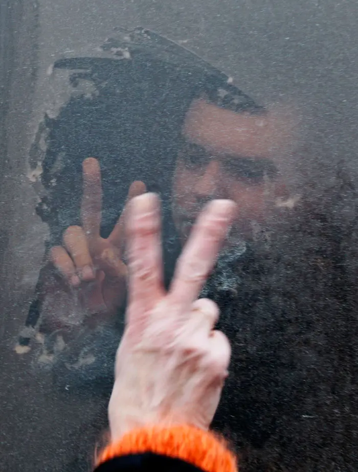 אחד מעצורי האופוזיציה מסמן תנועת ניצחון לצלמים מתוך אוטובוס שהוביל אותו למעצר במינסק