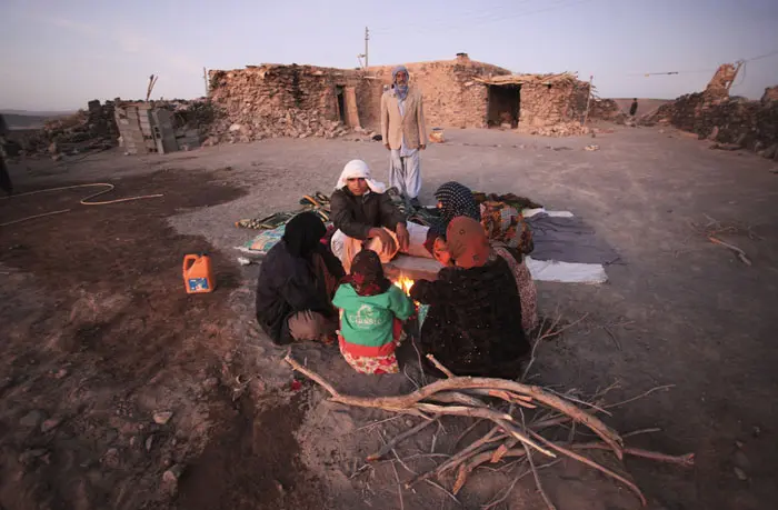 משפחה מתחממת ליד המדורה מחוץ לביתה שנהרס ברעש אדמה במחוז קרמאן בדרום-מזרח אירן
