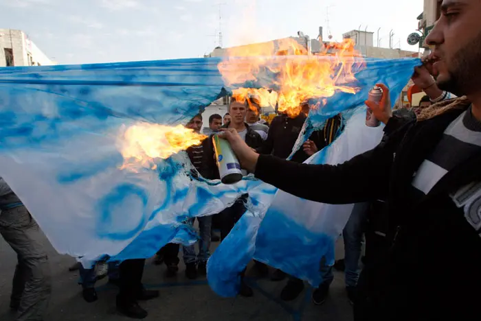 פלסטינים שורפים דגל ישראל מחוץ למשרדי רשת אל ג'זירה ברמאללה