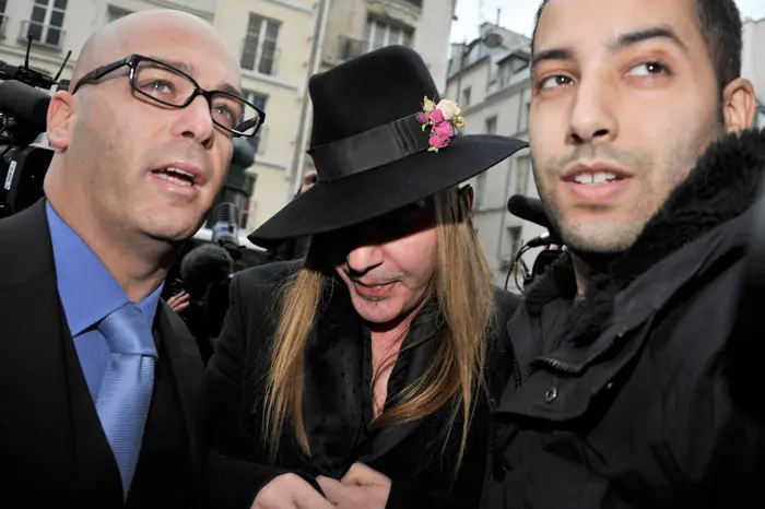 ג'ון גליאנו מלווה בשני עורכי דינו בתחנת המשטרה של פריז