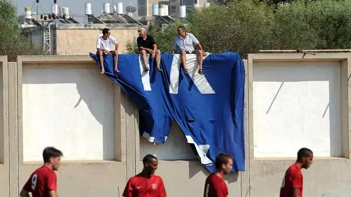 אוהדי מכבי קביליו יפו יושבים על החומה במשחק ללא קהל מול הפועל קטמון