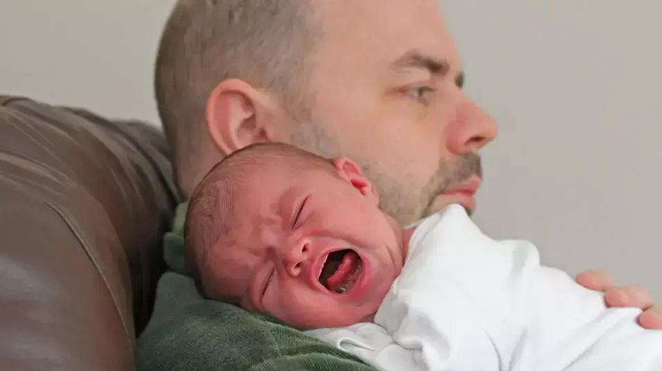 תינוק בוכה על כתף של מבוגר