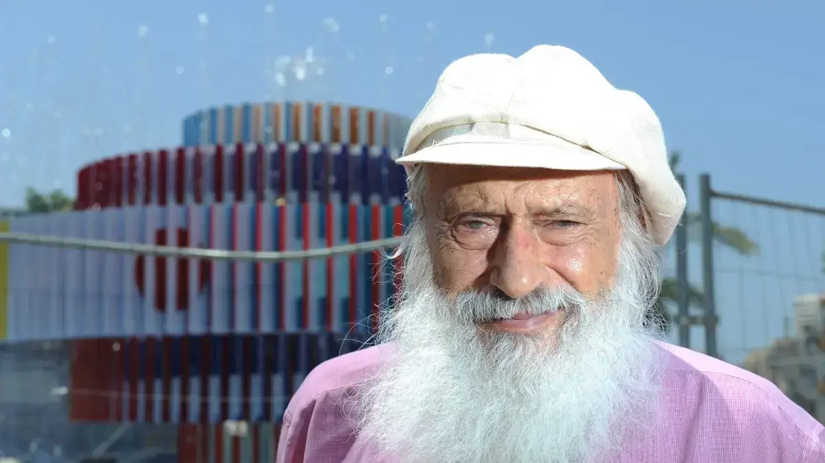 יעקב אגם על רקע המזרקה אותה יצר בכיכר דיזנגוף לפני פירוקה במסגרת שיפוץ הכיכר. תל אביב, יולי 2012